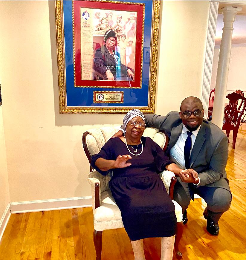 Jeremy Q. Henry kneeling beside Mother Willie Mae Rivers in her home