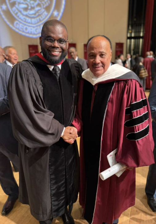 Jeremy Q. Henry in academic regalia shaking hands with a fellow honoree at a Martin Luther King, Jr. ceremony